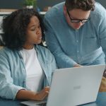 An experienced colleague coaching a team member at a laptop